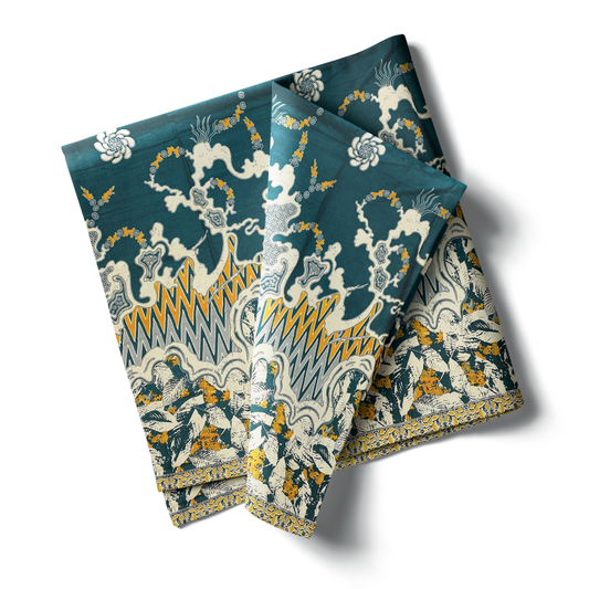 kain Katun Zig-Zag Daun dengan motif abstrak bergelombang, masing-masing dengan kombinasi warna yang berbeda (biru, cokelat, dan hijau). Kain dilipat dan diletakkan di samping hiasan pinus.